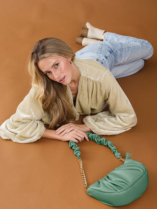 Dark Fern ruched shoulder bag with gold chain strap, worn crossbody.