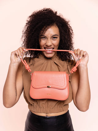 Fiji vegan curved shoulder bag in coral pink on model, front flap and short handles