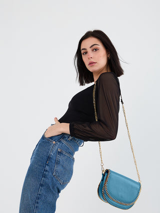 Blue chain-trim crossbody on model, flap closure and gold-tone shoulder chain