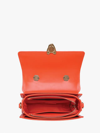 Orange crossbody bag interior view with snap top, zipper pocket, and gold hardware