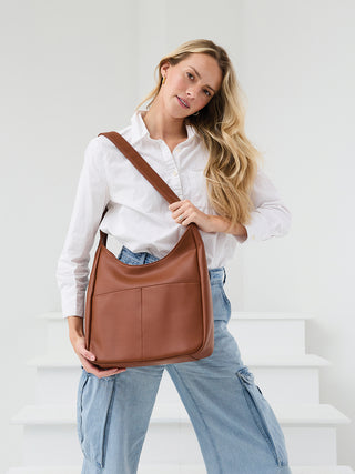 Brown vegan soft hobo bag held by model with wide strap and relaxed shape